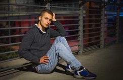 Young man sitting alone in an urban setting at night, reflecting on life after incarceration, prisoner reentry, rehabilitation, second chances, and hope for a successful future.